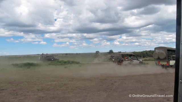 Tourists on African safari watching wildebeests crossing the Mara in Kenya